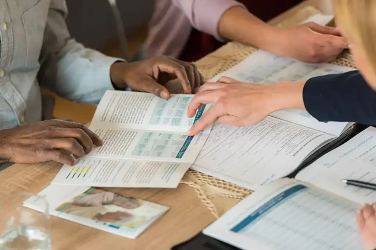 Réunion de travail pour impression 3 volets avec des personnes examinant un dépliant commercial.